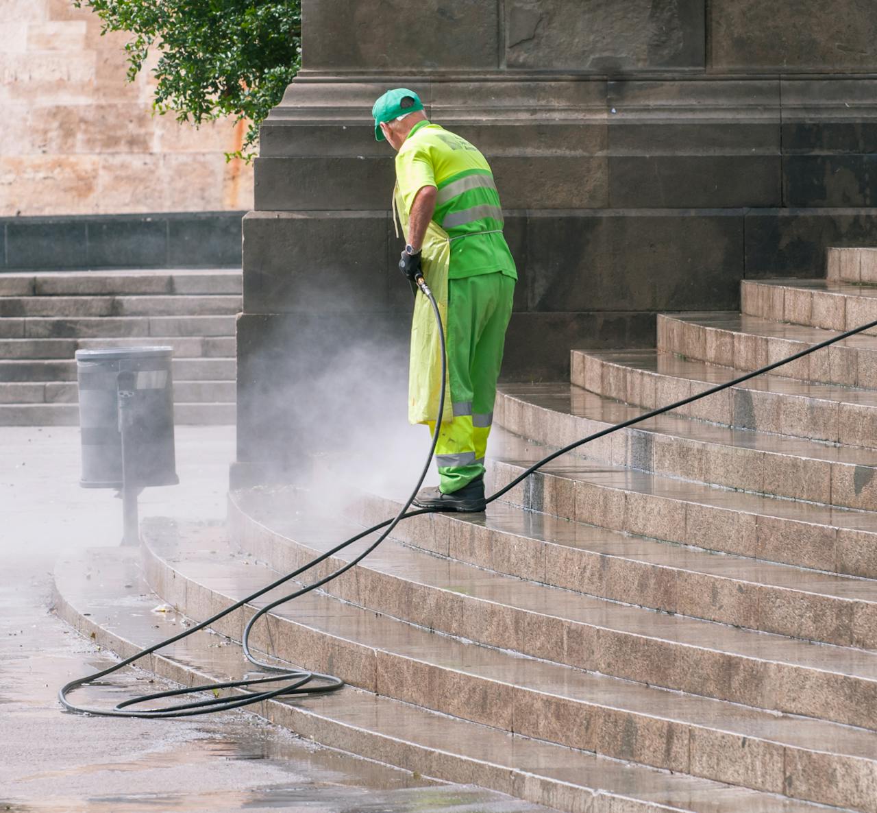 services-06 A street worker pressure washes stone stairs in a public park, ensuring cleanliness and safety.